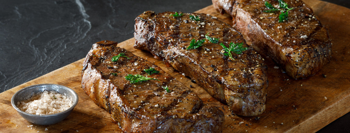 grilled ribeye steaks on cutting board