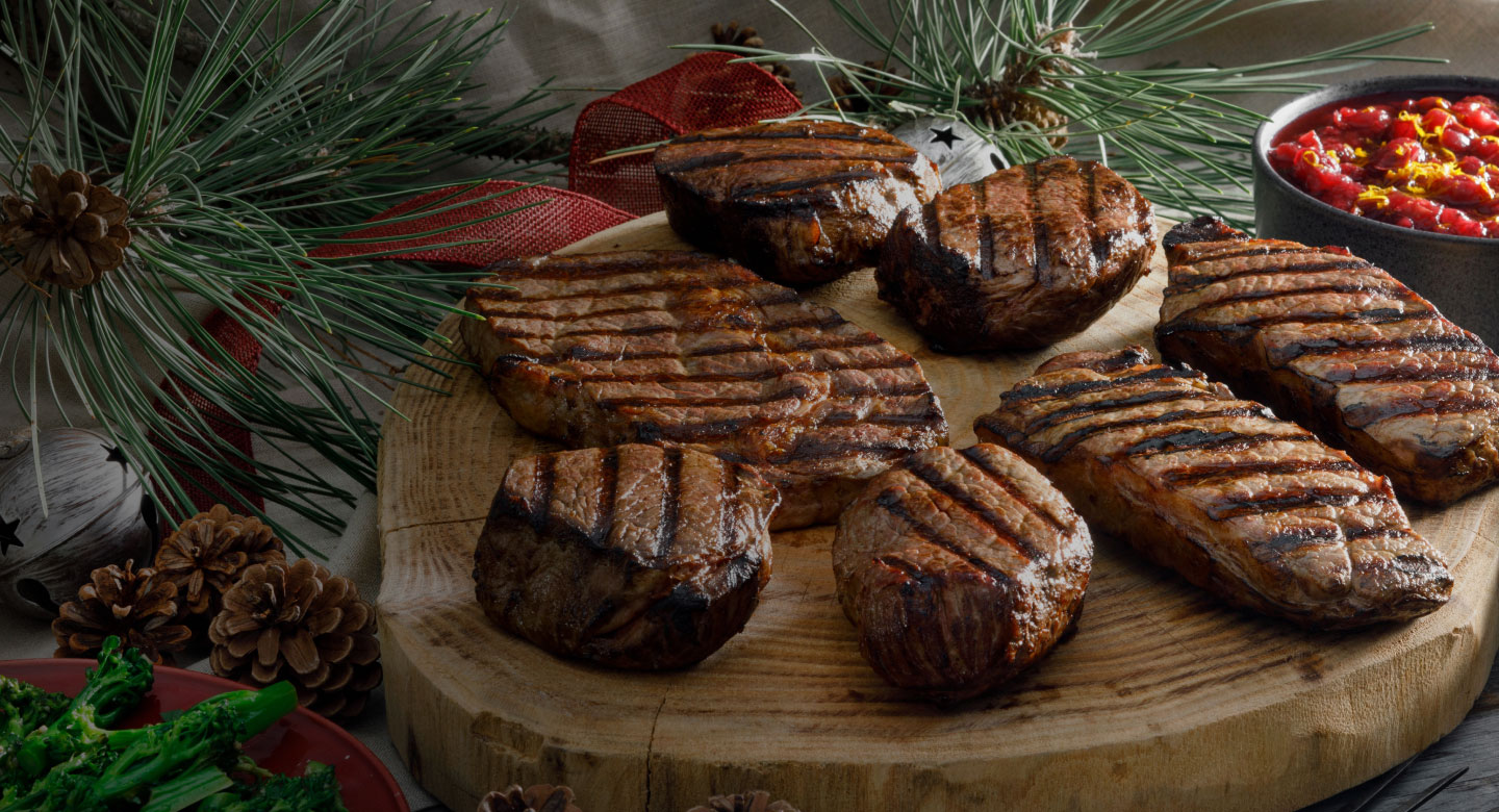 Grilled steaks on a wooden board with festive decorations